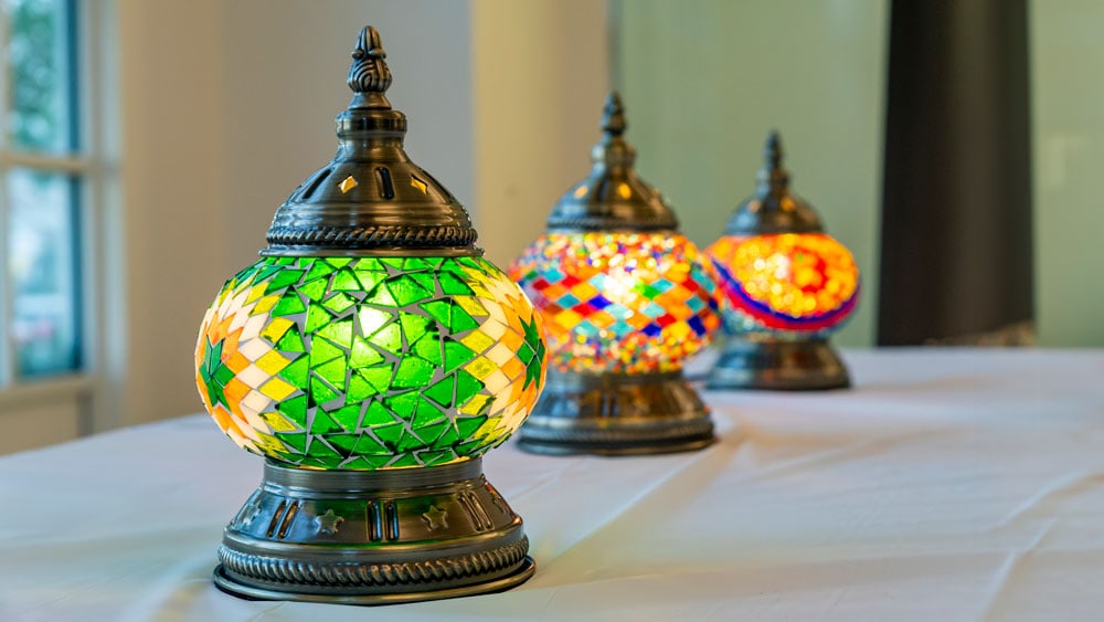 Green Turkish lamp with geometric star pattern and brass base alongside colorful mosaic table lamps