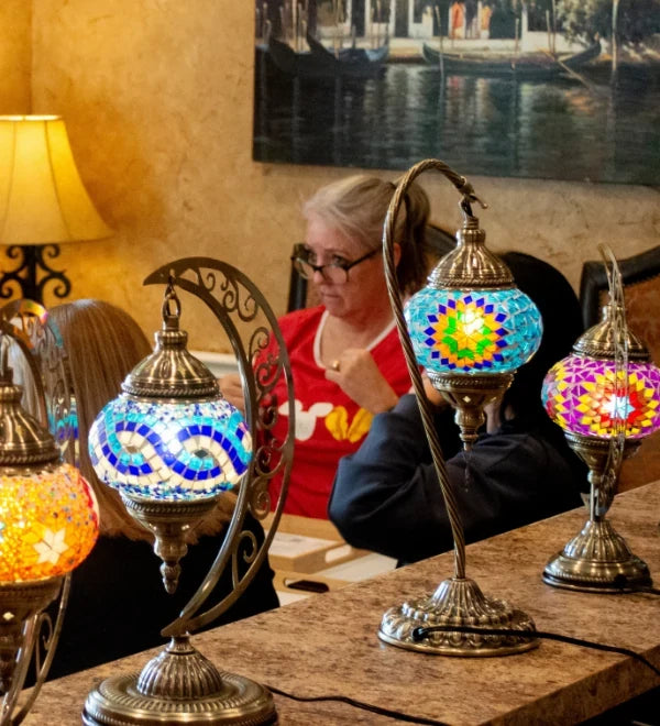 Lit Turkish mosaic lamps on the table during a craft night with friends