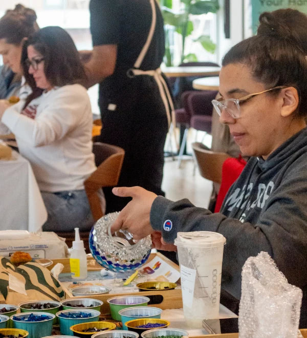 Woman carefully placing glass pieces on her first mosaic lamp