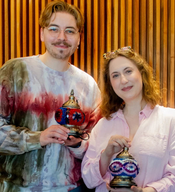 Two friends smiling with the mosaic lamps they made