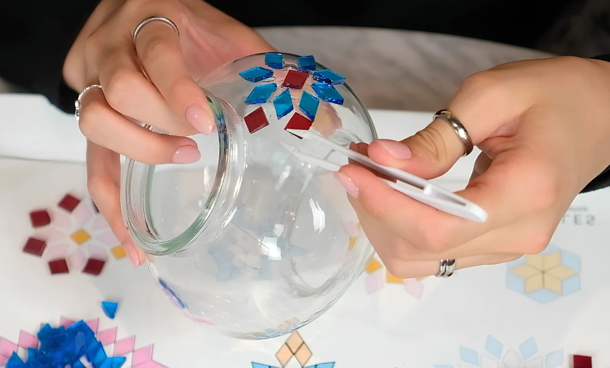Placing glass pieces on a clear lamp globe with tweezers